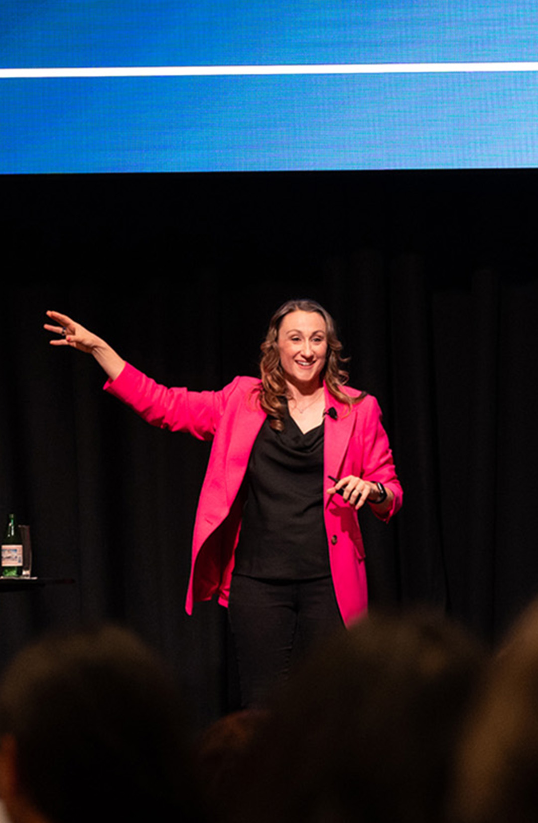 Abbie White (also searched as Abbey White or Abby White) delivering a keynote onstage with one arm raised.